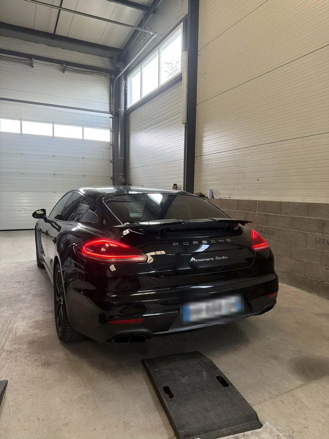 Porsche Panamera noire dans l’atelier, vue de l’arrière